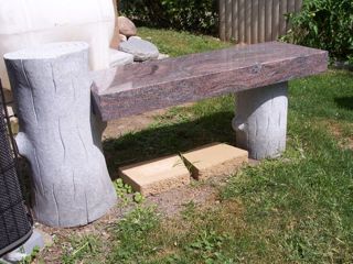 Bench in granite with wooden log supports