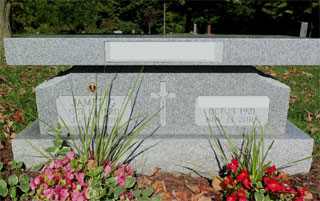 Gray granite double memorial with cross between names