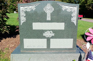 Gray granite double memorial with celtic cross at top center, flowers at upper corners