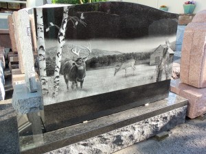 Black granite monument with outdoors scene with deer on display at Karl Lutz Monument Company