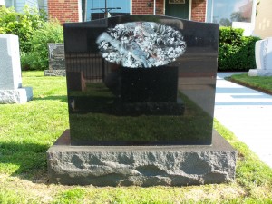 Black granite monument with birds and flowers on display at Karl Lutz Monument Company