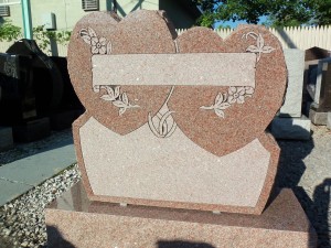 Mountain Rose granite monument with intertwined hearts, wedding rings, and flowers