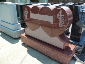 Red granite monument with intertwined hearts, crosses, and roses at Karl Lutz Monument Company